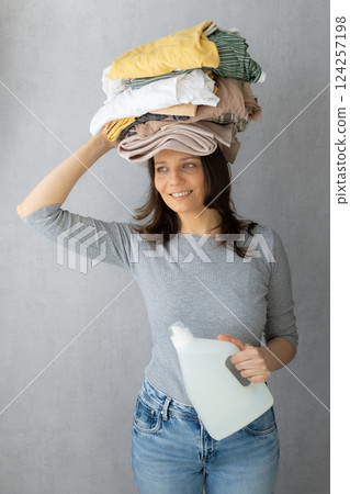 washing clothes, woman holds stack clothes on her head conditioner for laundry after dry cleaning. washing clothes, woman holds stack clothes on her head conditioner for laundry after dry cleaning. 124257198