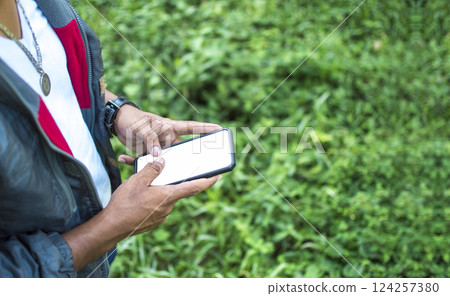 Close up of a man with cell phone in hand, close up of hands with cell phone with white screen, young guy with cell phone in hand with copy space Close up of a man with cell phone in hand, close up of hands with cell phone with white screen, young guy with cell phone in hand with copy space 124257380