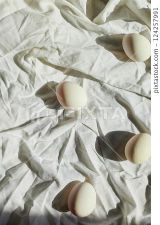 Easter-themed still life with white eggs arranged on a wrinkled fabric backdrop capturing spring's festive spirit 124257991