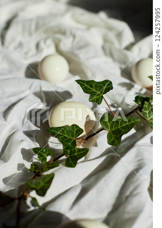Spring nature decor with white eggs and fresh ivy leaves for Easter celebration Spring nature decor with white eggs and fresh ivy leaves for Easter celebration 124257995
