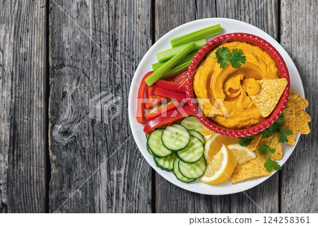 creamy roast carrot hummus in red bowl 124258361
