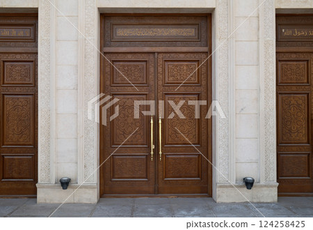 Three wooden doors with golden handles in front of a stone building Three wooden doors with golden handles in front of a stone building 124258425