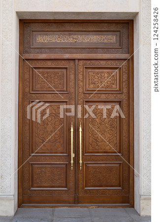 Ornate Wooden Carved Doorway with Gold Handles Ornate Wooden Carved Doorway with Gold Handles 124258426