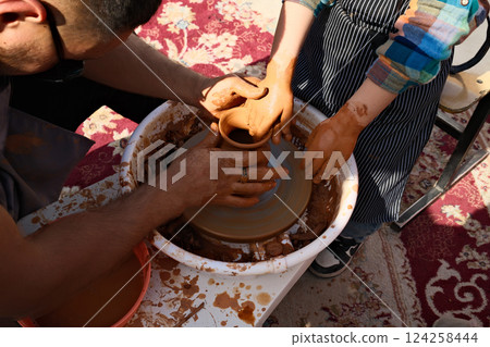 Making clay pottery by a master together with a kid 124258444