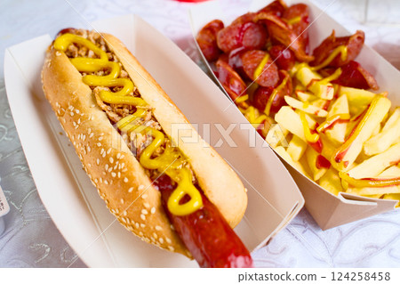 Delicious hot dog with mustard, sausage, and fries 124258458