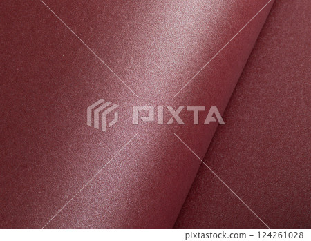 Elegant dark burgundy paper texture with a shimmering, glittering finish and subtly rolled edges. 124261028