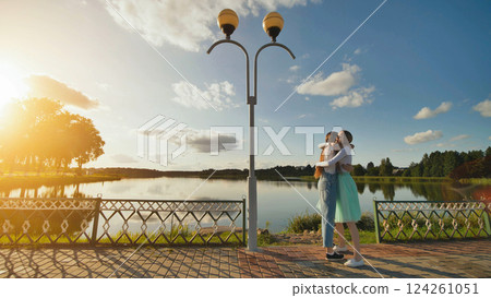 Teenage friends embracing near lakeside during golden sunset, sharing close bond and emotional connection Teenage friends embracing near lakeside during golden sunset, sharing close bond and emotional connection 124261051