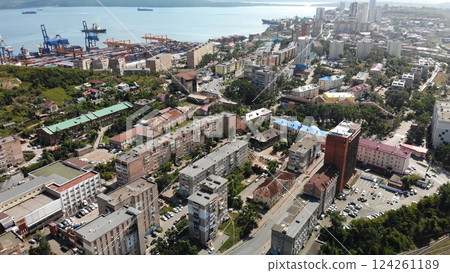Aerial view of a bustling port city, featuring cargo ships docking near a residential area filled with apartment buildings Aerial view of a bustling port city, featuring cargo ships docking near a residential area filled with apartment buildings 124261189