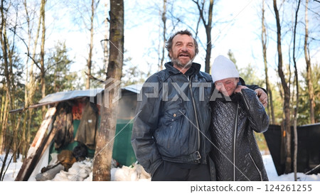 Homeless couple hugging near ramshackle shelter, winter forest revealing hardship of addiction and economic struggle Homeless couple hugging near ramshackle shelter, winter forest revealing hardship of addiction and economic struggle 124261255