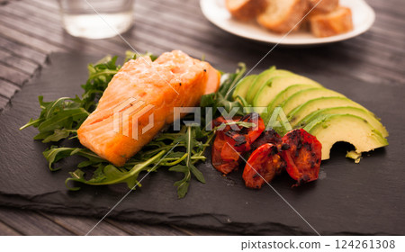Baked sea trout fillet with fresh vegetables and herbs on black board Baked sea trout fillet with fresh vegetables and herbs on black board 124261308