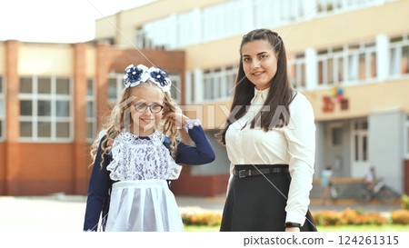 Two Russian schoolgirls sisters posing in festive clothes on the day of the beginning of the school year. Two Russian schoolgirls sisters posing in festive clothes on the day of the beginning of the school year. 124261315