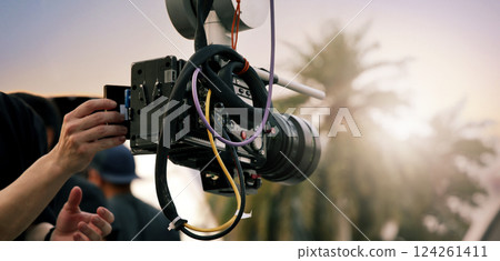 Video or film production with high tech robotic arm equipped with a professional cinema camera. Operated by a cinematographer. Advanced motion control system enables precise camera movements filming. 124261411