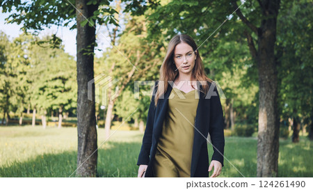Female professional strolling through lush park during spring, breathing fresh outdoor atmosphere 124261490