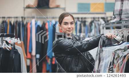 Customer browsing trendy garments on hangers in fashion boutique, enjoying shopping experience 124261493