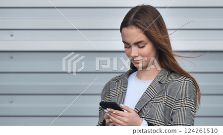Stylish businesswoman using mobile phone app, browsing internet, checking email or social media, standing outdoors near modern office building Stylish businesswoman using mobile phone app, browsing internet, checking email or social media, standing outdoors near modern office building 124261510