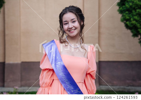 Young graduate student smiling, wearing a graduation sash, celebrating academic achievement and the end of school Young graduate student smiling, wearing a graduation sash, celebrating academic achievement and the end of school 124261593