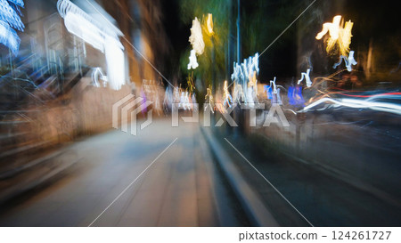 Light trails illuminating a dark city street at night, creating a dynamic abstract with motion blur 124261727