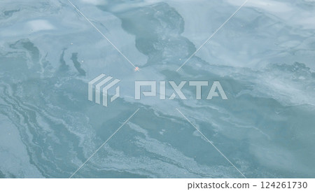 Iridescent oil slick spreading across ocean surface, revealing environmental damage from petroleum contamination of marine waters 124261730
