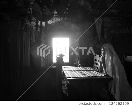 A girl sits at a table by the window in an ancient castle A girl sits at a table by the window in an ancient castle 124262309