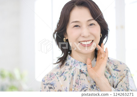 A smiling middle-aged woman wearing a floral blouse 124263271