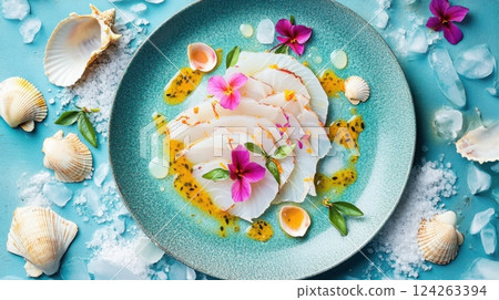 Thinly sliced mahi-mahi carpaccio is elegantly presented on a turquoise plate, surrounded by seashells and ice. Passion fruit reduction and hibiscus petals enhance its tropical appeal. 124263394