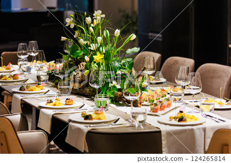 Elegant floral centerpiece with white tulips and lush greenery on a luxurious dining table 124265814