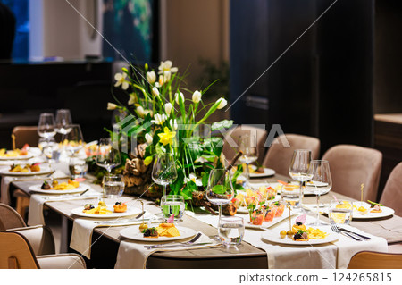 Elegant floral centerpiece with white tulips and lush greenery on a luxurious dining table Elegant floral centerpiece with white tulips and lush greenery on a luxurious dining table 124265815