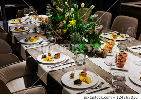 Elegant floral centerpiece with white tulips and lush greenery on a luxurious dining table 124265816