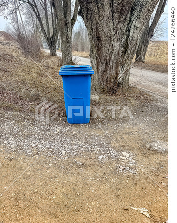 Blue Garbage Bin on Rural Gravel Path, Trees in Background, Outdoor Waste Management, Natural Setting. High quality photo 124266440