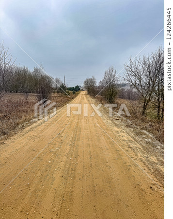 Empty Dirt Road Through Rural Landscape, Cloudy Sky, Natural Scenery, Travel, Remote Location. High quality photo Empty Dirt Road Through Rural Landscape, Cloudy Sky, Natural Scenery, Travel, Remote Location. High quality photo 124266445