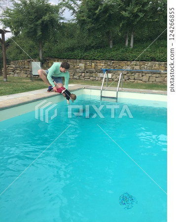 Father Helping Child Dip Hand in Pool Water 124266855