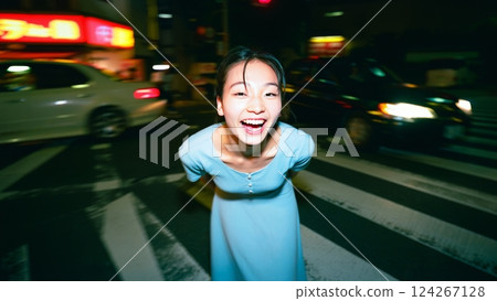 A flash-lit shot of a young woman wearing an elegant dress, in the middle of a busy city at night. Youth and happiness concept A flash-lit shot of a young woman wearing an elegant dress, in the middle of a busy city at night. Youth and happiness concept 124267128