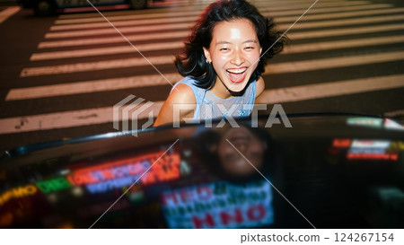 A flash-lit shot of a young woman wearing an elegant dress, in the middle of a busy city at night. Youth and happiness concept 124267154