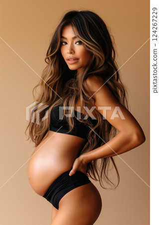 Calm and reflective photo of a pregnant woman confidently embracing her belly. Expresses themes of motherhood, natural beauty, and strength, with a serene pose enhancing its emotive impact. 124267229