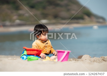 1 year old boy playing in the sand at the beach 124267437