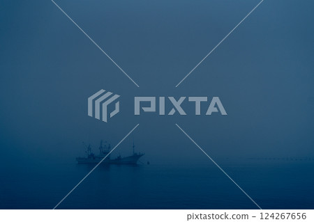 Fishing boats moored in harbor in heavy fog 124267656