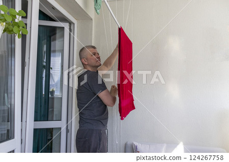 Man hangs the clothes on the roller dryer on the balcony 124267758