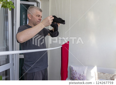 Man hangs the clothes on the roller dryer on the balcony 124267759