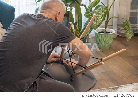Man tightening up a bolts of the stylish chair 124267762