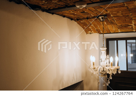 Interior with exposed electrical wiring on arched brick ceiling and vintage chandelier, blending rustic design with modern infrastructure. Visible wiring, interior design contrast, adaptive reuse. 124267764