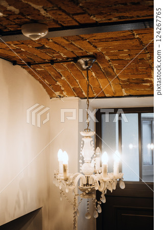 Interior with exposed electrical wiring on arched brick ceiling and vintage chandelier, blending rustic design with modern infrastructure. Visible wiring, interior design contrast, adaptive reuse. 124267765