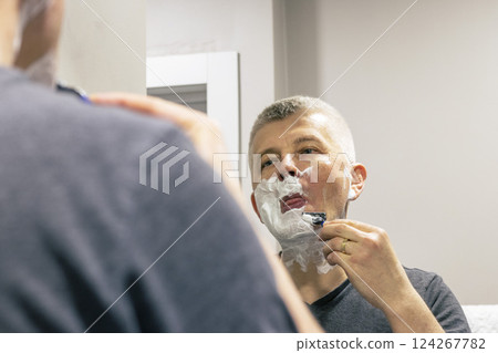 Reflection in the mirror of the man shaving 124267782