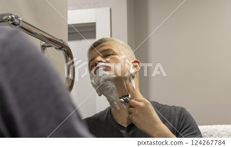 Reflection in the mirror of the man shaving Reflection in the mirror of the man shaving 124267784