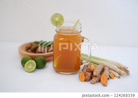 Fresh ginger and lemon juice in a glass jar with ginger roots on white background. Fresh ginger and lemon juice in a glass jar with ginger roots on white background. 124268339