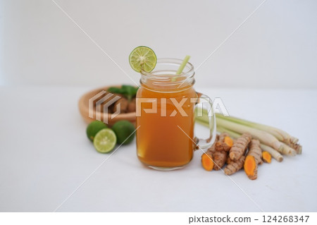 Fresh ginger and lemon juice in a glass jar with ginger roots on white background. Fresh ginger and lemon juice in a glass jar with ginger roots on white background. 124268347