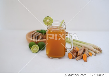 Fresh ginger and lemon juice in a glass jar with ginger roots on white background. Fresh ginger and lemon juice in a glass jar with ginger roots on white background. 124268348