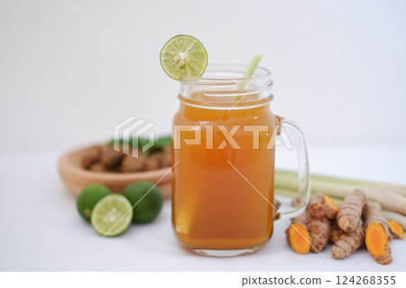 Fresh ginger and lemon juice in a glass jar with ginger roots on white background. 124268355