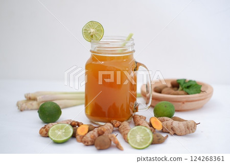 Fresh ginger and lemon juice in a glass jar with ginger roots on white background. Fresh ginger and lemon juice in a glass jar with ginger roots on white background. 124268361