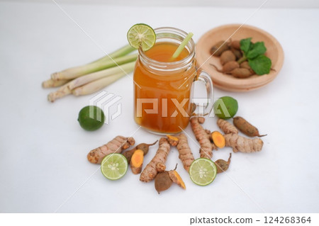 Fresh ginger and lemon juice in a glass jar with ginger roots on white background. Fresh ginger and lemon juice in a glass jar with ginger roots on white background. 124268364