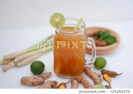 Fresh ginger and lemon juice in a glass jar with ginger roots on white background. 124268370